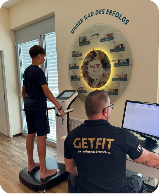 Jugendlicher steht f&uuml;r die InBody-Analyse auf dem Messger&auml;t, ein GET-FIT-Coach wertet die Werte am Bildschirm aus